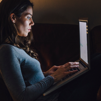 Woman sitting in a room, surfing on her laptop