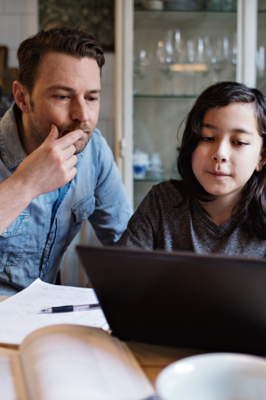 Father and daughter studying together using a laptop